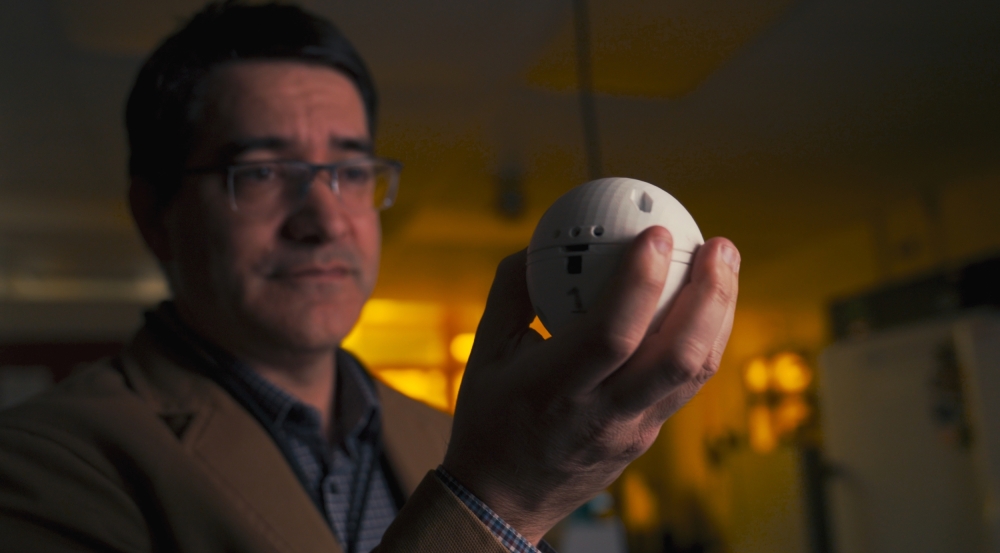 A man holds a baseball-sized 3D printed ball in his hand. The ball is a chemical sensor that can be thrown. 