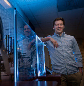 Photo of Ryan Burrow standing next to a glass display