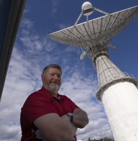 A photograph of Noah Stein standing in front of a radar. 