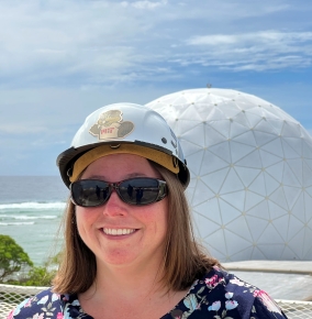 Sarah Willis wearing a hard hat in front of a radome at Kwajalein Field Site