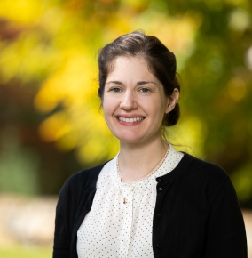 A portrait photograph with blurred trees in autumn in the background.