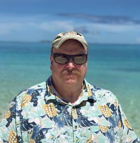 A portrait photograph of John O'Rourke, with the ocean in the background.