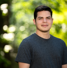 A portrait of David Langus Rodriguez outside with greenery in the background