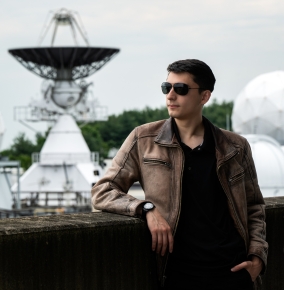 Photo of Madison Lagos standing outside with a large radar in the background.