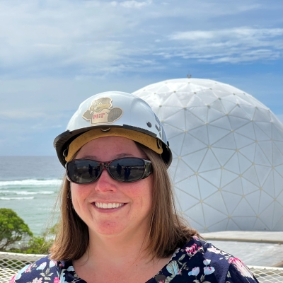 Sarah Willis wearing a hard hat in front of a radome at Kwajalein Field Site
