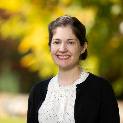 A portrait photograph with blurred trees in autumn in the background.