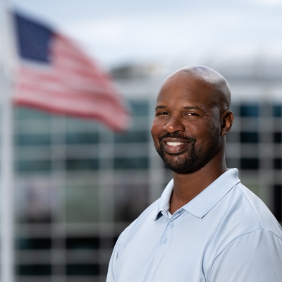 Henrie Young poses for a photo outside, with the U.S. flag in the background. 