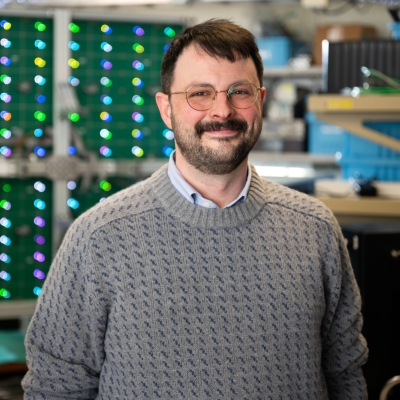 A photograph of Michael Craton standing in front of a reflectarray antenna.