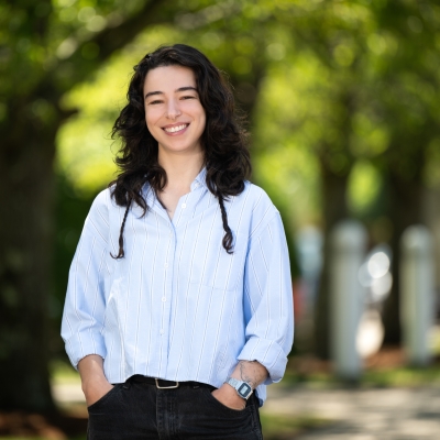 Mirit Rutishauser stands outside and smiles with green trees in the background.