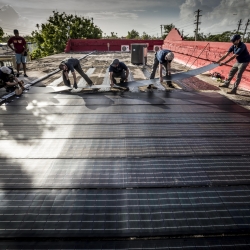 All hands are on deck as the team adheres the solar modules onto the roof of the Boys and Girls Club. Photo: Lorenzo Moscia