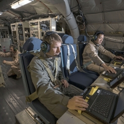 MIT Lincoln Laboratory personnel Joseph Zurkus, left, and Jacob Huang, right, operate a protected tactical waveform modem and collect data while Ted O’Connel monitors terminal equipment to ensure everything is working properly during flight testing Oct. 5