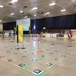 The race course for the Obstacles Trial. The three obstacles (from left) were a pillar, a hoop, and a gate. The flags indicate the required path that the drone must fly through while the black squares are Augmented Reality Codes for drones to detect.