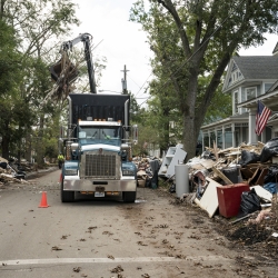 A photo of a large truck picking up debris lining a street