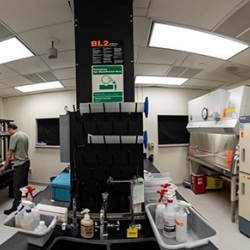 A researcher stands at a benchtop in a laboratory