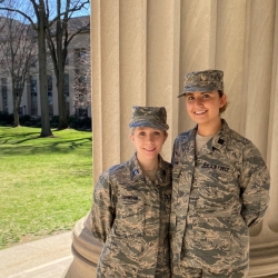 Two US Air Force cadets smile for a photo in the MIT courtyard.