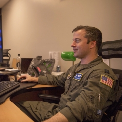 An Air Force pilot sits at a computer screen in an office. 