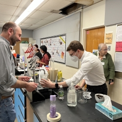 Two instructors in a classroom to fill a beaker with water.