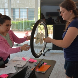 A photo of Esmeralda Hernandez and Liz Raine spinning a wheel above a small radar system they built.