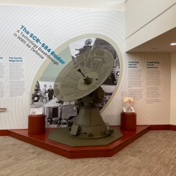 A photograph of the SCR-584 radar at Lincoln Laboratory in front of a wall of text about its development and use in World War II.