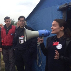 Steph Foster speaks through a megaphone to a gathering of first responders and officials.