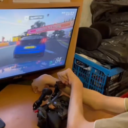 Levis, a co-designer with cerebral palsy, is playing the racing game Forza with a customized Xbox controller.