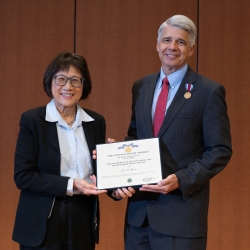 Heidi Shyu and Eric Evans stand side by side holding Evans' award for the Department of Defense Medal for Distinguished Public Service. Evans is pinned with the medal.