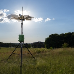 a sensor/instrument on a tripod, set up in a field.