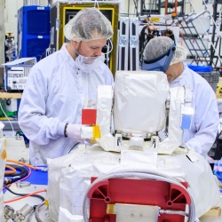 At Kennedy Space Center, Laboratory staff members Justin Dunbeck (left) and Steven Constantine unpack and examine the Optical Communications System payload for NASA's Artemis II mission to the Moon. Photo: NASA/Glenn Benson.