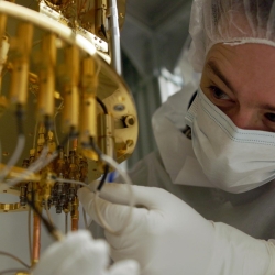 A researcher makes adjustments to a dilution refrigerator, a large piece of hardware for cooling quantum systems.