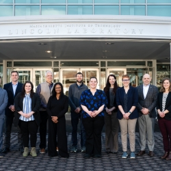 A group photo of PMI and MIT LL team outside of the main Lincoln Laboratory entrance.