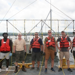 A group of researchers smile on a boat for a group photo. 