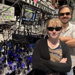 Lincoln Laboratory researchers Lucy Gray Shamel and Will Setzer wear protective glasses while standing next to the optics systems they used for the research. 