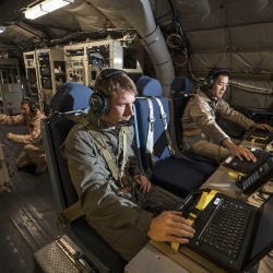 Lincoln Laboratory personnel Joseph Zurkus, left, and Jacob Huang, right, operate a protected tactical waveform modem and collect data while Ted O'Connell, back, monitors terminal equipment during flight testing.