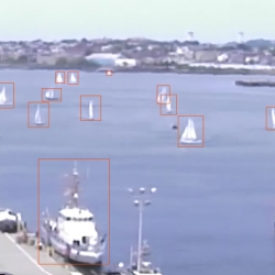 a photo of boston harbor with several boats on the water; each boat has an orange box drawn around it as a 'detection'