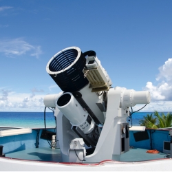 A photograph of a large optical system, with the ocean in the background. 