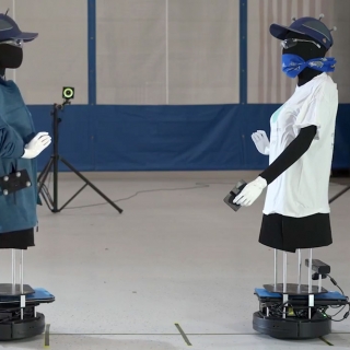 Two robots (dressed as human mannequins) face eachother.