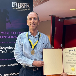 A photo of a man holding an award he received.