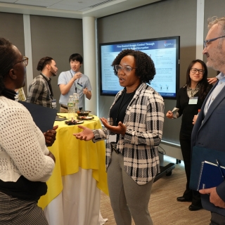 three people talking around a high top table at a poster session