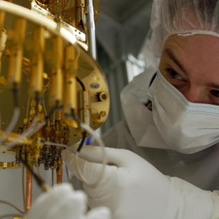 A researcher makes adjustments to a dilution refrigerator, a large piece of hardware for cooling quantum systems.