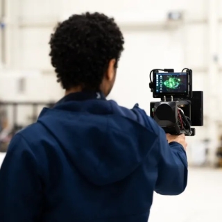 Lincoln Laboratory researcher Noah Yared holds a DePLife prototype. His back is showing in the image with the prototype screen in front and visible. 