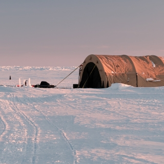 A large tent and supplies sit atop ice in the Arctic. 