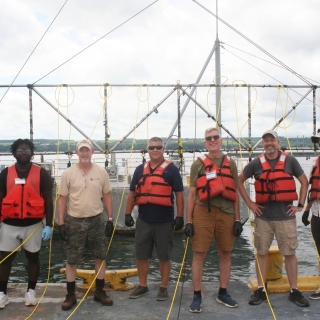 A group of researchers smile on a boat for a group photo. 