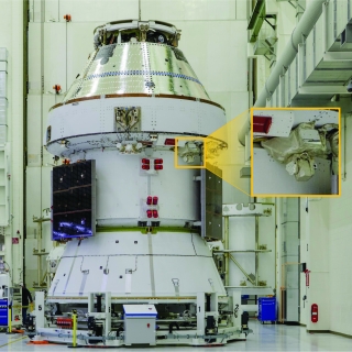 A spacecraft sits inside Kennedy Space Center. A callout box outlines where a laser communications terminal is located on the spacecraft.