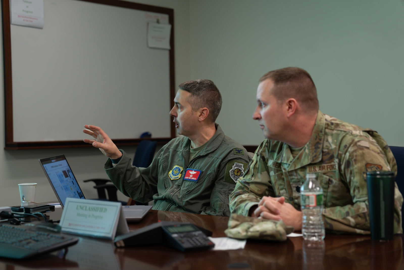 Colonel Joseph Monaco, left, and Lieutenant Colonel Tim Heaton sit at a table discussing a presentation they are being briefed on.
