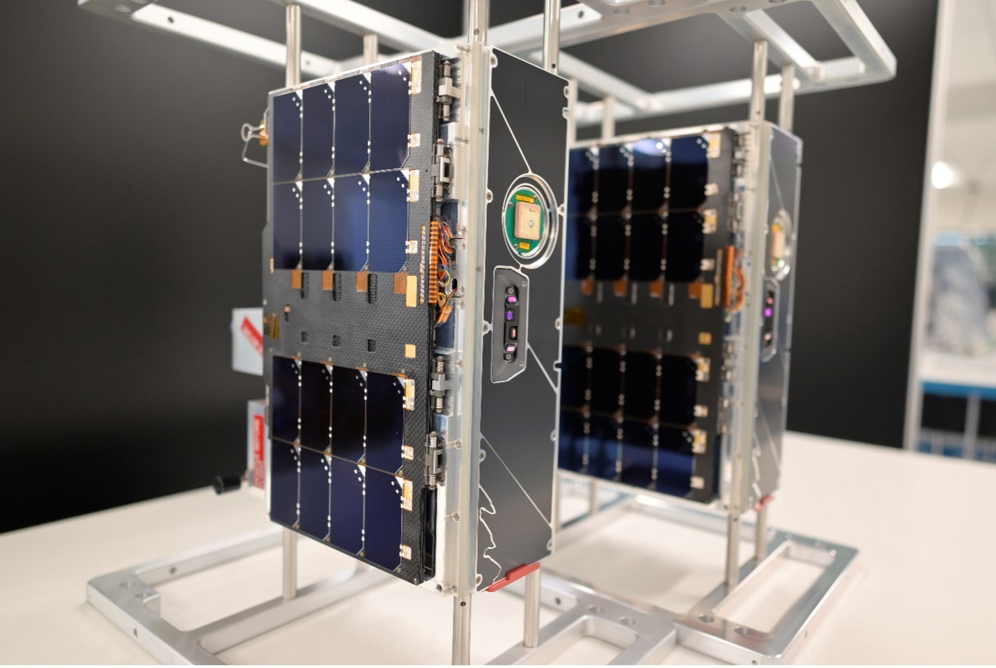 Two CubeSats (roughly 20 x 10 x 30 cm in size) are shown in a lab setting 