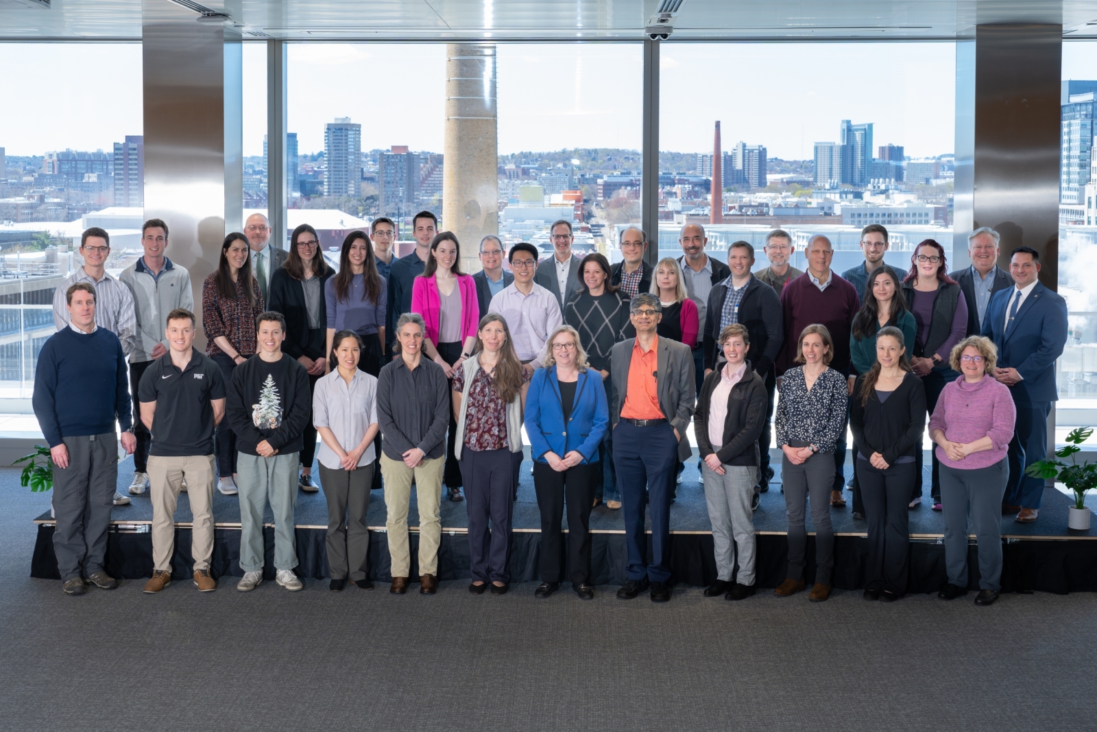 Luncheon attendees gather for a photo with windows in the background. 