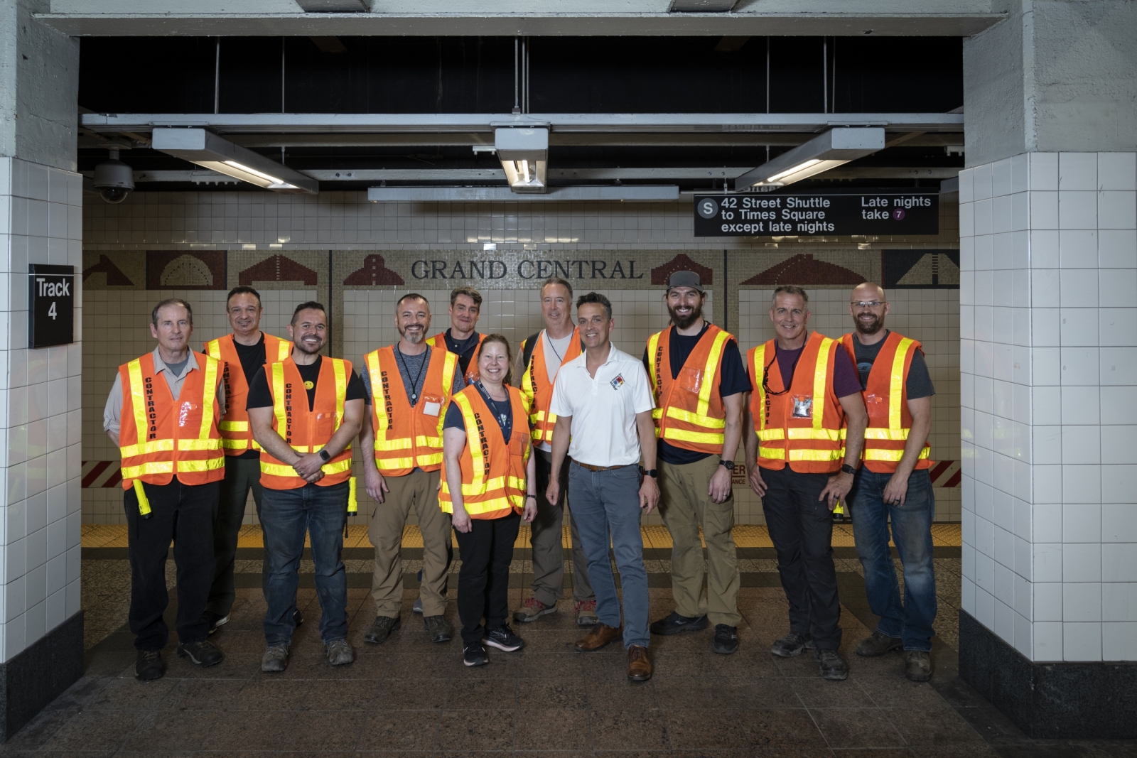 The Lincoln Laboratory, MTA, and Sandia National Laboratories project teams are gathered for a photo in the subway wearing orange vests.