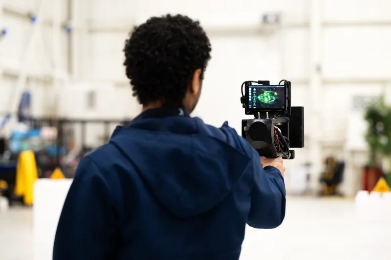 Lincoln Laboratory researcher Noah Yared holds a DePLife prototype. His back is showing in the image with the prototype screen in front and visible. 