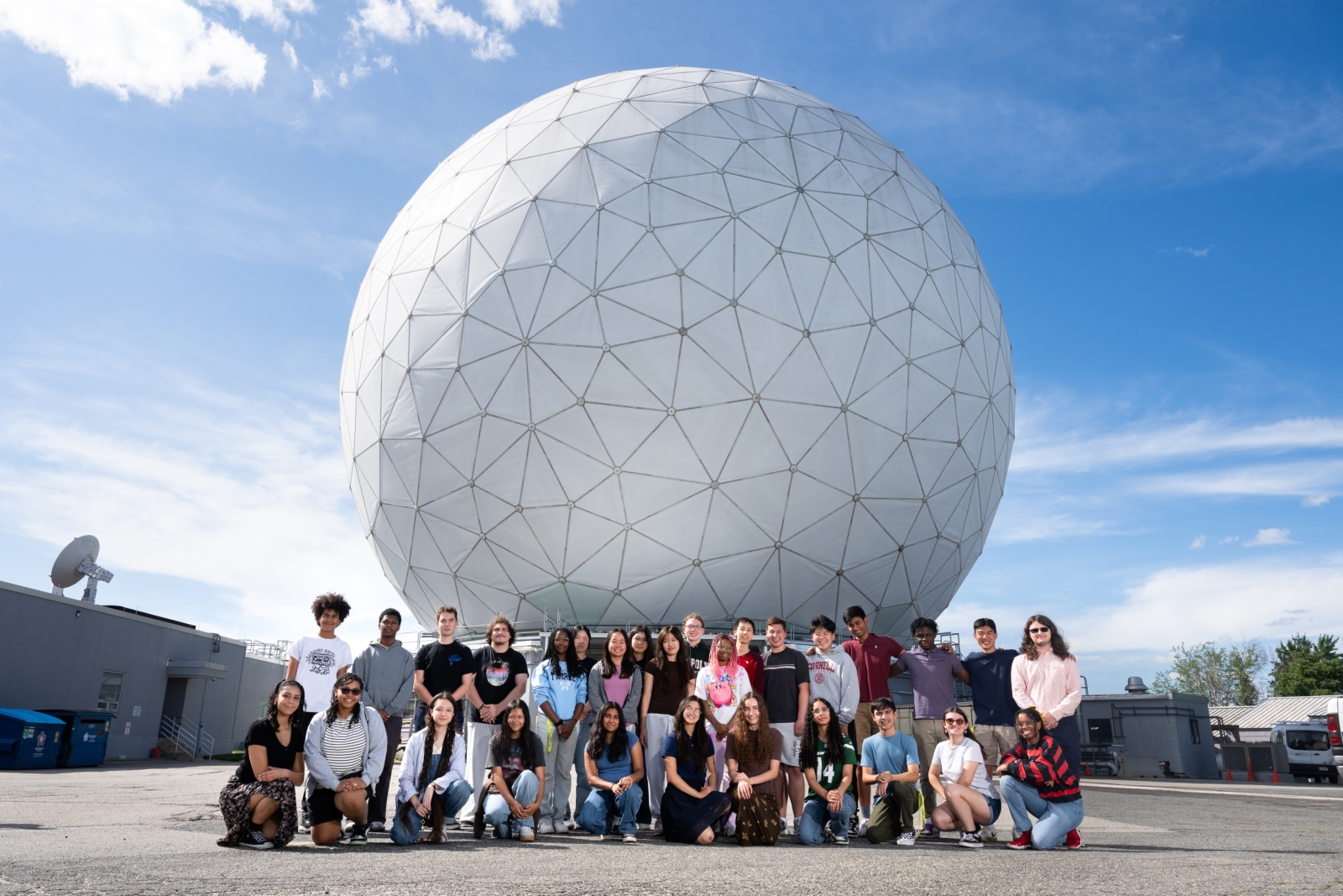 LLRISE students gather outside the Haystack Ultrawideband Satellite Imaging Radar dome on a clear day.