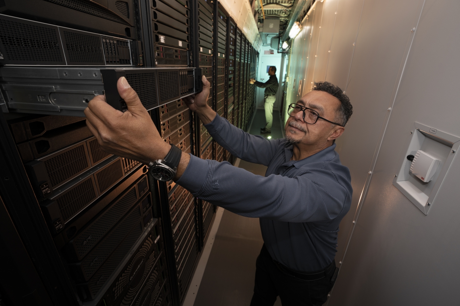 A photo of system engineer Antonio Rosa inspecting server equipment inside a data center. 